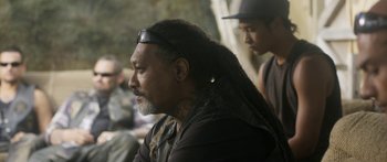 Movie still from “The Dark Horse” (2014), directed by James Napier Robertson – A man with long black hair and a long beard; Close Up shot, Over the shoulder angle