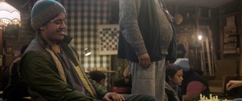Movie still from “The Dark Horse” (2014), directed by James Napier Robertson – A man standing next to another man in front of a checkerboard wall; Medium shot, Over the shoulder angle