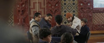 Movie still from “The Dark Horse” (2014), directed by James Napier Robertson – A group of people standing around a wall; Medium shot, Over the shoulder angle