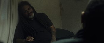Movie still from “The Dark Horse” (2014), directed by James Napier Robertson – A man with dreadlocks sitting on a couch; Medium shot, High angle