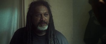 Movie still from “The Dark Horse” (2014), directed by James Napier Robertson – A person with dreadlocks and a beard; Close Up shot, Over the shoulder angle