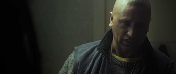 Movie still from “The Dark Horse” (2014), directed by James Napier Robertson – A bald man wearing a sweater and a jacket; Close Up shot, Low angle