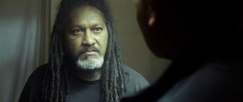 A man with dreads looking into a mirror