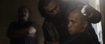 Movie still from “The Dark Horse” (2014), directed by James Napier Robertson – A man standing next to another man in a dark room; Medium shot, Over the shoulder angle