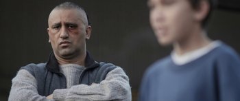 Movie still from “The Dark Horse” (2014), directed by James Napier Robertson – A man in a sweater with a bruised face; Close Up shot, Over the shoulder angle