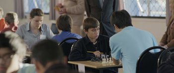 Movie still from “The Dark Horse” (2014), directed by James Napier Robertson – A young man sitting at a table playing chess; Close Up shot, Over the shoulder angle