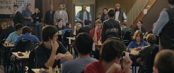 Movie still from “The Dark Horse” (2014), directed by James Napier Robertson – A group of people sitting around a room playing chess; Wide shot, Over the shoulder angle
