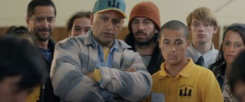 Movie still from “The Dark Horse” (2014), directed by James Napier Robertson – A group of people standing next to each other in a room; Medium shot, Over the shoulder angle