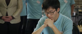 Movie still from “The Dark Horse” (2014), directed by James Napier Robertson – A young man with glasses is sitting down with his hands clasped together; Close Up shot, High angle