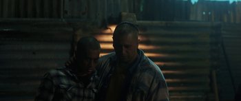 Movie still from “The Dark Horse” (2014), directed by James Napier Robertson – Two men standing next to each other in a dark room; Medium shot, Low angle