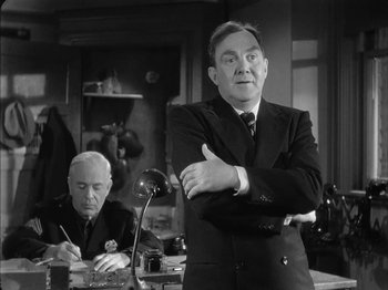 Movie still from “The Dark Mirror” (1946), directed by Robert Siodmak – A man standing in front of another man in a room; Medium shot, Over the shoulder angle