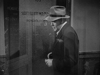 Movie still from “The Dark Mirror” (1946), directed by Robert Siodmak – A black and white photo of a man wearing a suit and a hat; Medium shot, Over the shoulder angle