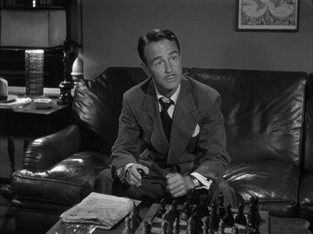 Movie still from “The Dark Mirror” (1946), directed by Robert Siodmak – A black and white photo of a man sitting on a couch; Close Up shot, High angle