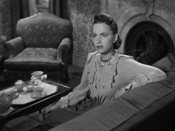 Movie still from “The Dark Mirror” (1946), directed by Robert Siodmak – A black and white photo of a woman sitting on a couch; Medium shot, High angle