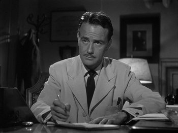Movie still from “The Dark Mirror” (1946), directed by Robert Siodmak – A black and white photo of a man in a suit and tie writing; Medium shot, Low angle