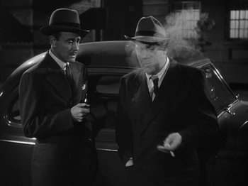Movie still from “The Dark Mirror” (1946), directed by Robert Siodmak – Two men standing next to each other in front of a car; Medium shot, Low angle