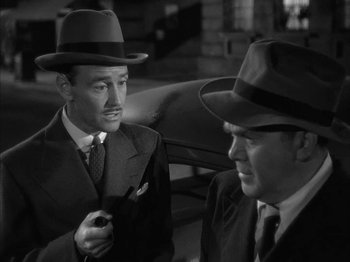 Movie still from “The Dark Mirror” (1946), directed by Robert Siodmak – A man in a suit and a man in a hat talking to each other; Close Up shot, High angle