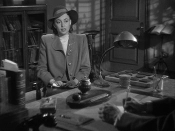 Movie still from “The Dark Mirror” (1946), directed by Robert Siodmak – A black and white photo of a woman sitting at a table; Medium shot, Over the shoulder angle