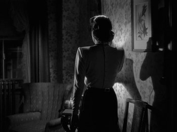Movie still from “The Dark Mirror” (1946), directed by Robert Siodmak – A black and white photo of a woman standing in front of a wall; Medium shot, Low angle