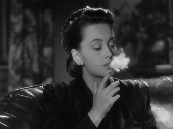 Movie still from “The Dark Mirror” (1946), directed by Robert Siodmak – A black and white photo of a woman smoking a cigarette; Close Up shot, High angle