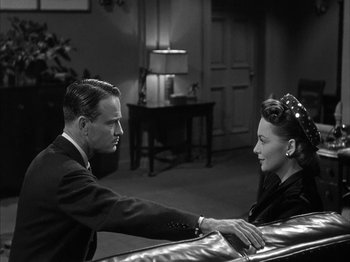 Movie still from “The Dark Mirror” (1946), directed by Robert Siodmak – A man and a woman are holding hands in a living room; Medium shot, Over the shoulder angle