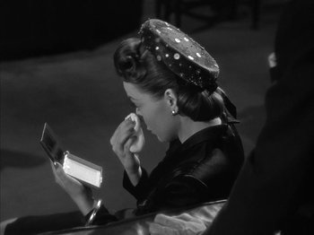 Movie still from “The Dark Mirror” (1946), directed by Robert Siodmak – A black and white photo of a woman looking at her phone; Medium shot, High angle