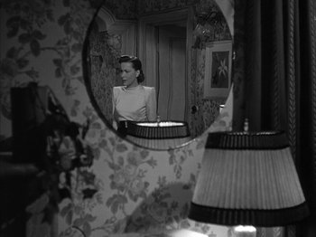 Movie still from “The Dark Mirror” (1946), directed by Robert Siodmak – A black and white photo of a woman looking in a mirror; Medium shot, High angle
