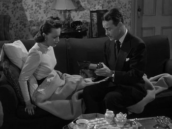 Movie still from “The Dark Mirror” (1946), directed by Robert Siodmak – A man and a woman sitting on a couch looking at each other; Medium shot, High angle