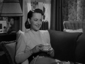 Movie still from “The Dark Mirror” (1946), directed by Robert Siodmak – A black and white photo of a woman sitting on a couch holding a cup; Medium shot, High angle