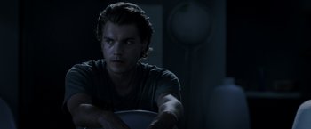 Movie still from “The Darkest Hour” (2011), directed by Chris Gorak – A man sitting in a dark room holding a frisbee; Close Up shot, Low angle