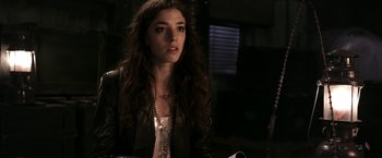 Movie still from “The Darkest Hour” (2011), directed by Chris Gorak – A woman with long brown curly hair sitting in a dark room; Close Up shot, Over the shoulder angle