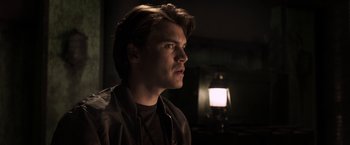 Movie still from “The Darkest Hour” (2011), directed by Chris Gorak – A young man is standing in front of an oil lamp; Close Up shot, Low angle