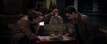 Movie still from “The Darkest Hour” (2011), directed by Chris Gorak – Two people are looking at a birdcage in a dark room; Medium shot, Low angle