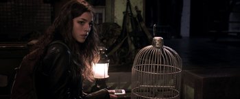 Movie still from “The Darkest Hour” (2011), directed by Chris Gorak – A woman holding a cell phone next to a bird cage; Close Up shot, Low angle