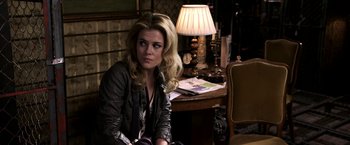 Movie still from “The Darkest Hour” (2011), directed by Chris Gorak – A woman sitting in front of a table in a room; Medium shot, Over the shoulder angle