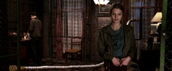 Movie still from “The Darkest Hour” (2011), directed by Chris Gorak – A woman standing in a room with a metal pipe; Medium shot, Over the shoulder angle