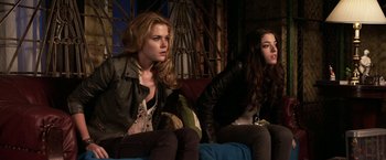 Movie still from “The Darkest Hour” (2011), directed by Chris Gorak – Two women sitting on a blue couch in a room; Medium shot, Low angle