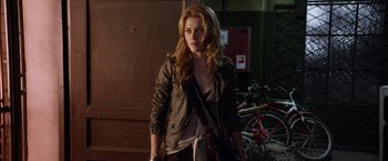 Movie still from “The Darkest Hour” (2011), directed by Chris Gorak – A beautiful young woman holding a purse while standing next to bicycles; Medium shot, Over the shoulder angle