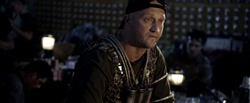 Movie still from “The Darkest Hour” (2011), directed by Chris Gorak – A man wearing chains and a black hat; Close Up shot, Over the shoulder angle