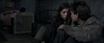 Movie still from “The Darkest Hour” (2011), directed by Chris Gorak – A young woman sitting next to a young man in front of a fireplace; Medium shot, Over the shoulder angle