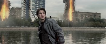 Movie still from “The Darkest Hour” (2011), directed by Chris Gorak – A man standing in front of a building on fire; Medium shot, Low angle