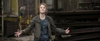 Movie still from “The Darkest Hour” (2011), directed by Chris Gorak – A woman in a jacket standing next to a pile of wood; Medium shot, Low angle