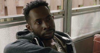 Movie still from “The Day Shall Come” (2019), directed by Christopher Morris – A person sitting in front of a window; Close Up shot, Over the shoulder angle