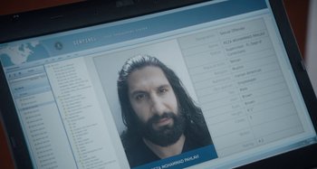 Movie still from “The Day Shall Come” (2019), directed by Christopher Morris – A computer screen showing a picture of a man with long hair; Extreme Close Up shot, Overhead angle