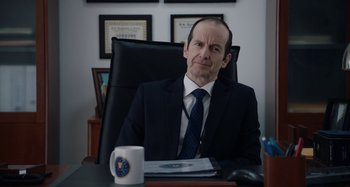 Movie still from “The Day Shall Come” (2019), directed by Christopher Morris – A man sitting at a desk in front of a coffee mug; Close Up shot, Over the shoulder angle