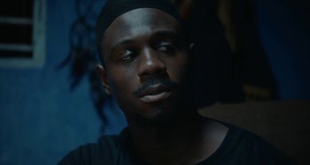 Movie still from “The Day Shall Come” (2019), directed by Christopher Morris – A person wearing a black hat; Close Up shot, Low angle