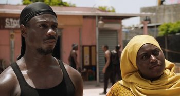 Movie still from “The Day Shall Come” (2019), directed by Christopher Morris – A man and a woman standing next to each other in front of a building; Close Up shot, Over the shoulder angle