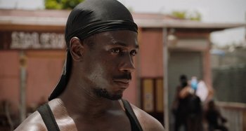 Movie still from “The Day Shall Come” (2019), directed by Christopher Morris – A person wearing a black hat; Close Up shot, Over the shoulder angle