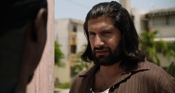 Movie still from “The Day Shall Come” (2019), directed by Christopher Morris – A person with long hair and a beard; Close Up shot, Over the shoulder angle