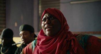 Movie still from “The Day Shall Come” (2019), directed by Christopher Morris – A woman in a red headscarf is looking up; Close Up shot, Over the shoulder angle